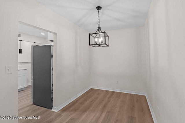 2295 Wood St, Melbourne, FL 32904 - unfurnished dining area featuring light wood-style flooring, a chandelier, and baseboards