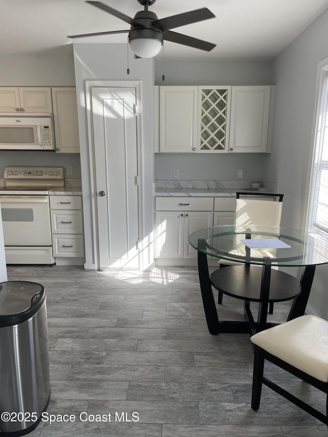 115 E Colonial Ct Unit C, Indian Harbour Beach, FL 32937 - kitchen with white appliances, a ceiling fan, wood finished floors, and white cabinetry
