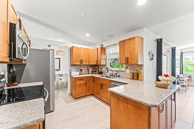 740 Hunan St NE, Palm Bay, FL 32907 - kitchen featuring stainless steel microwave, a peninsula, backsplash, brown cabinetry, and light stone countertops