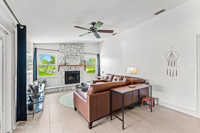740 Hunan St NE, Palm Bay, FL 32907 - living room with light wood-style flooring, a ceiling fan, a textured ceiling, and a fireplace