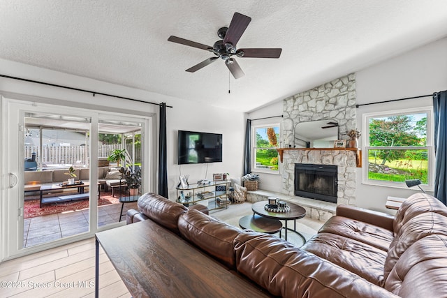 740 Hunan St NE, Palm Bay, FL 32907 - living room with a textured ceiling, a ceiling fan, vaulted ceiling, and a stone fireplace