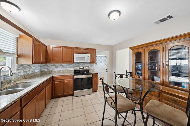 926 Caligula Ave SE, Palm Bay, FL 32909 - kitchen with stainless steel range with electric stovetop, white microwave, a sink, tasteful backsplash, and light tile patterned floors