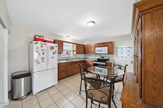 926 Caligula Ave SE, Palm Bay, FL 32909 - kitchen featuring white appliances, a sink, backsplash, light tile patterned floors, and brown cabinets