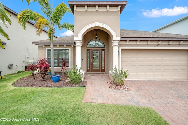 4299 Alligator Flag Cir, West Melbourne, FL 32904 - view of exterior entry with stucco siding, decorative driveway, roof with shingles, and a yard