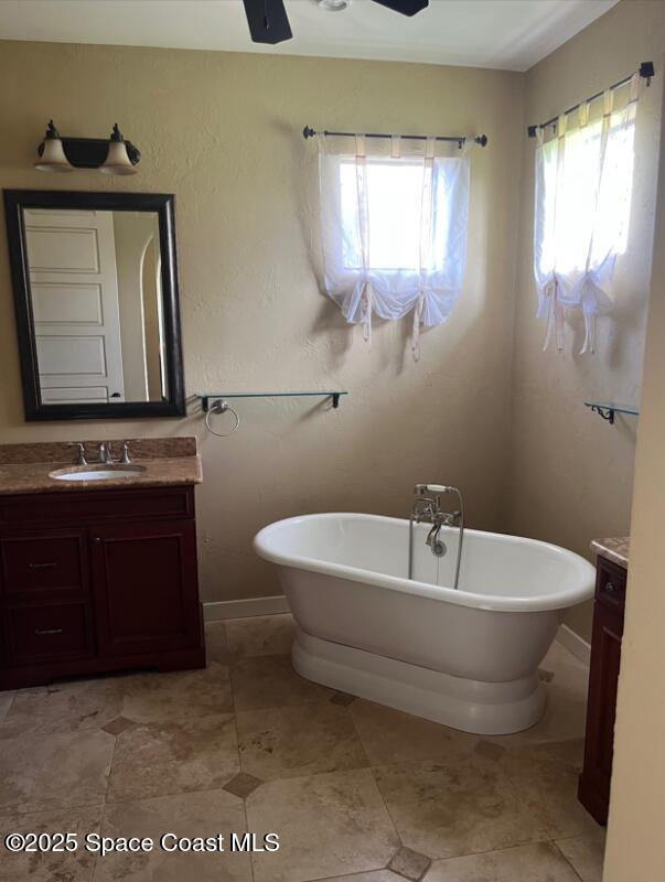 3180 Savannahs Trl, Merritt Island, FL 32953 - full bath with vanity, a soaking tub, baseboards, and a ceiling fan