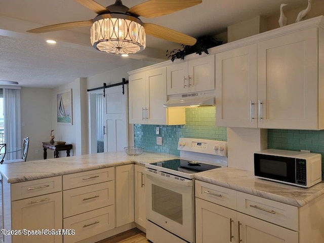 2100 N Atlantic Ave Unit 1207, Cocoa Beach, FL 32931 - kitchen with black microwave, white range with electric cooktop, under cabinet range hood, ceiling fan, and a peninsula