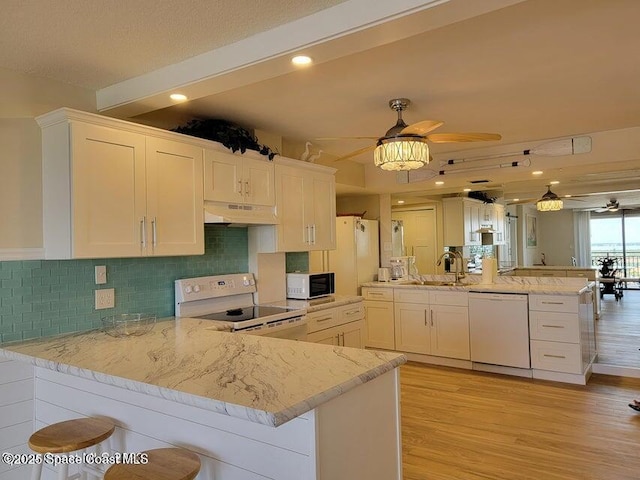 2100 N Atlantic Ave Unit 1207, Cocoa Beach, FL 32931 - kitchen with white appliances, under cabinet range hood, ceiling fan, a peninsula, and light wood-style floors