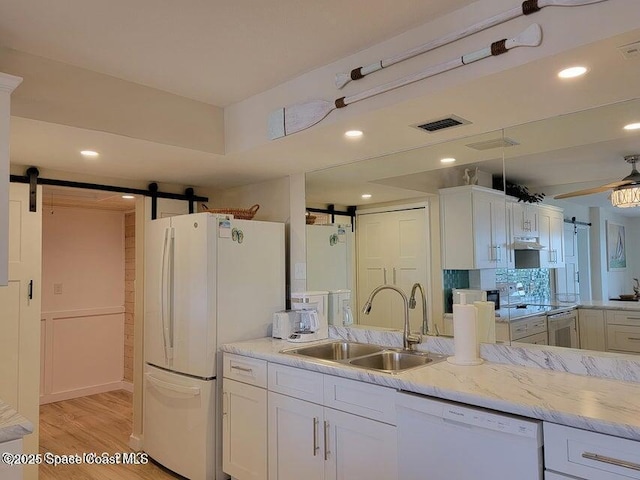2100 N Atlantic Ave Unit 1207, Cocoa Beach, FL 32931 - kitchen with a barn door, white appliances, a sink, light wood-style floors, and white cabinets
