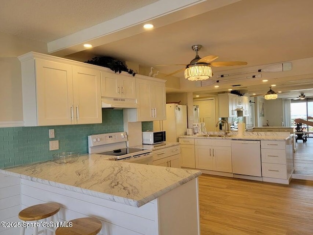 2100 N Atlantic Ave Unit 1207, Cocoa Beach, FL 32931 - kitchen with white appliances, under cabinet range hood, a peninsula, a ceiling fan, and light wood-style flooring