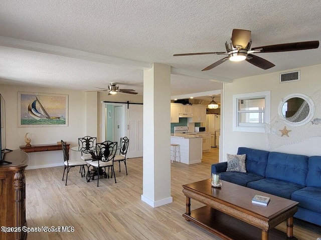2100 N Atlantic Ave Unit 1207, Cocoa Beach, FL 32931 - living room with a ceiling fan, a barn door, light wood-style flooring, a textured ceiling, and baseboards