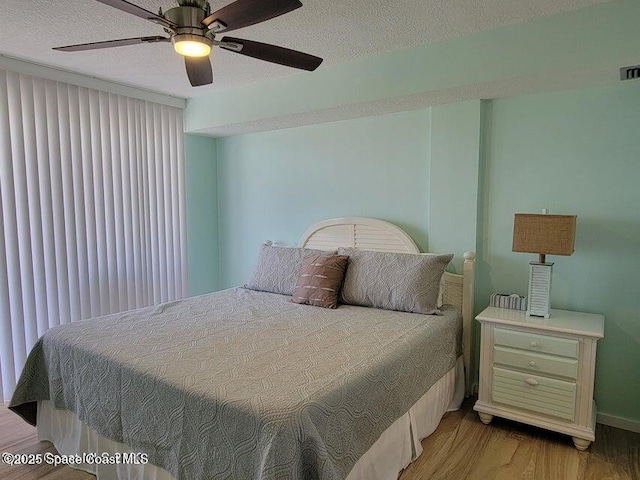 2100 N Atlantic Ave Unit 1207, Cocoa Beach, FL 32931 - bedroom with light wood-style floors, a textured ceiling, a ceiling fan, and baseboards