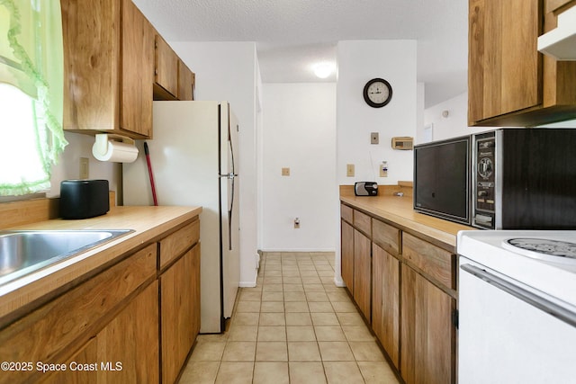 741 Alaska Ave NE, Palm Bay, FL 32907 - kitchen featuring light countertops, light tile patterned floors, freestanding refrigerator, and brown cabinets