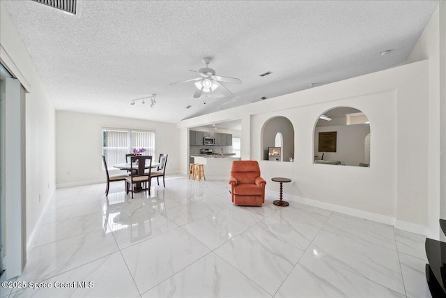 2125 Spring Creek Cir, Palm Bay, FL 32905 - living room with light marble finish floors, a ceiling fan, a textured ceiling, baseboards, and track lighting