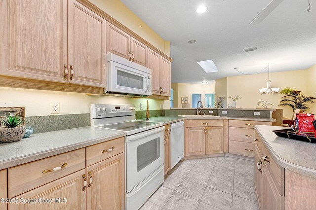 4224 Woodhall Cir, Rockledge, FL 32955 - kitchen featuring white appliances, light brown cabinets, a peninsula, a sink, and a skylight