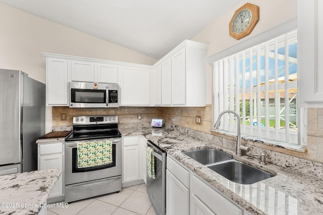 775 Triple Crown Ln, Melbourne, FL 32904 - kitchen featuring stainless steel appliances, a sink, vaulted ceiling, light tile patterned floors, and white cabinets