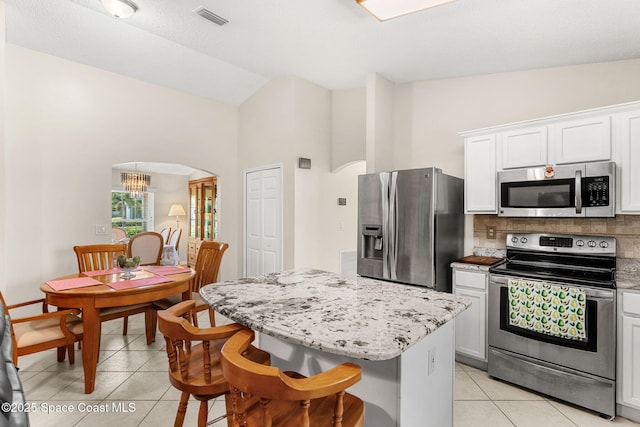 775 Triple Crown Ln, Melbourne, FL 32904 - kitchen featuring appliances with stainless steel finishes, arched walkways, light tile patterned flooring, backsplash, and a center island