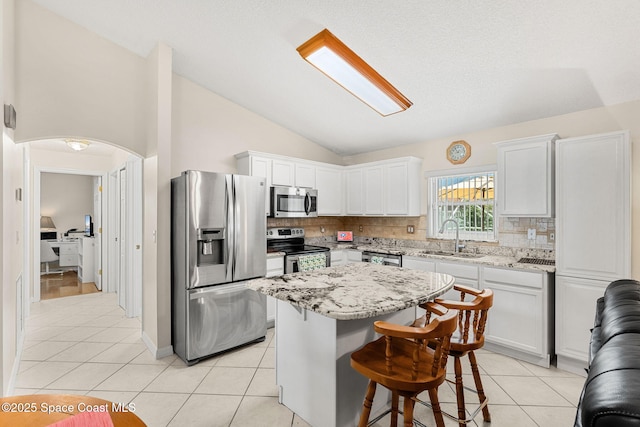 775 Triple Crown Ln, Melbourne, FL 32904 - kitchen with stainless steel appliances, a sink, vaulted ceiling, light tile patterned floors, and backsplash