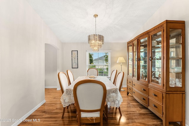 775 Triple Crown Ln, Melbourne, FL 32904 - dining area featuring arched walkways, a textured ceiling, a chandelier, wood finished floors, and baseboards