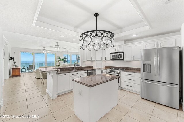 505 S Miramar Ave Unit 2403, Indialantic, FL 32903 - kitchen featuring appliances with stainless steel finishes, a raised ceiling, a sink, a peninsula, and white cabinetry