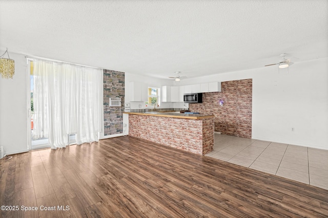 3820 Ocean Beach Blvd Unit 1, Cocoa Beach, FL 32931 - unfurnished living room with a ceiling fan, wood finished floors, and a textured ceiling