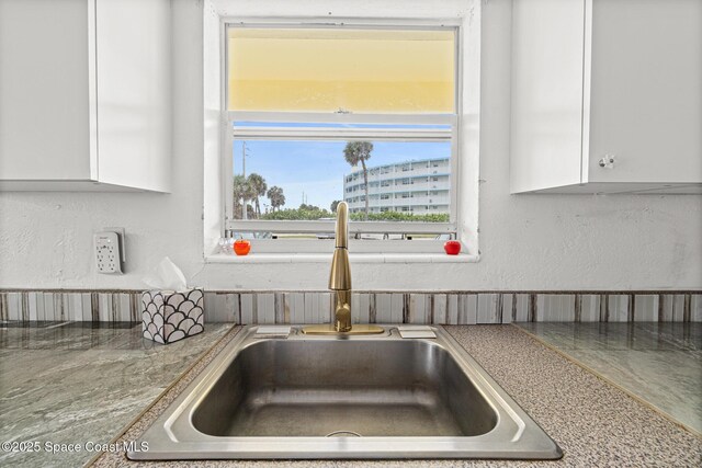 3820 Ocean Beach Blvd Unit 1, Cocoa Beach, FL 32931 - kitchen view of a sink, white cabinetry, and a textured wall