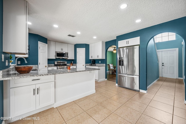 5256 Mansford Pl, Melbourne, FL 32940 - kitchen with appliances with stainless steel finishes, a textured ceiling, arched walkways, a peninsula, and light tile patterned flooring