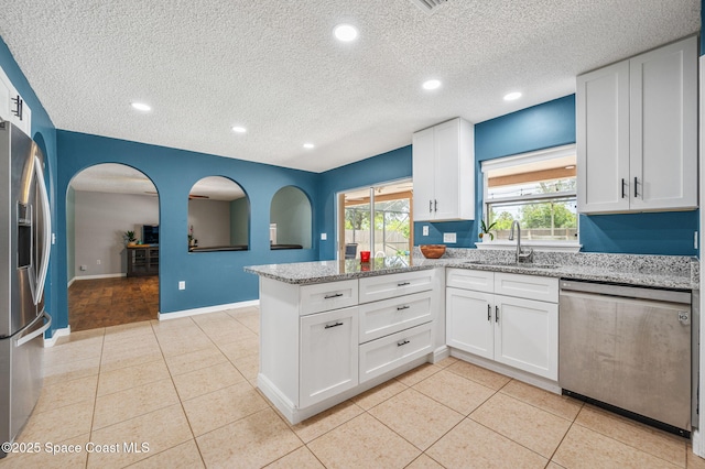 5256 Mansford Pl, Melbourne, FL 32940 - kitchen with appliances with stainless steel finishes, a sink, a peninsula, a textured ceiling, and white cabinetry