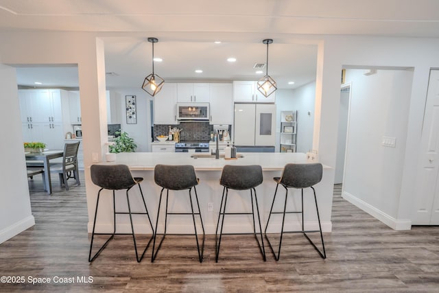 629 Tupelo Dr, Melbourne, FL 32935 - kitchen with white microwave, wood finished floors, a kitchen breakfast bar, recessed lighting, and light countertops