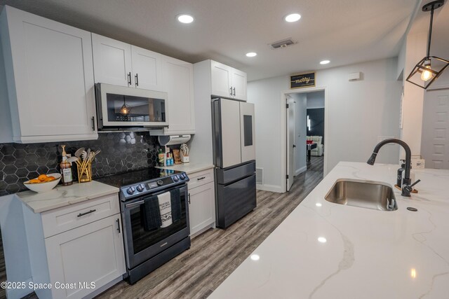 629 Tupelo Dr, Melbourne, FL 32935 - kitchen featuring stainless steel appliances, a sink, wood finished floors, backsplash, and white cabinets