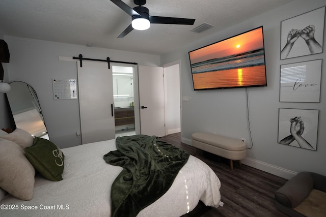 629 Tupelo Dr, Melbourne, FL 32935 - bedroom featuring wood finished floors, baseboards, a barn door, a textured ceiling, and a ceiling fan