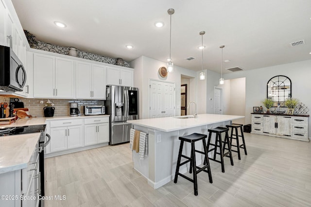 2365 Roygaris St NW, Palm Bay, FL 32907 - kitchen with appliances with stainless steel finishes, a sink, tasteful backsplash, an island with sink, and light countertops
