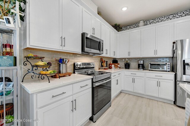 2365 Roygaris St NW, Palm Bay, FL 32907 - kitchen with appliances with stainless steel finishes, white cabinets, light stone counters, decorative backsplash, and recessed lighting