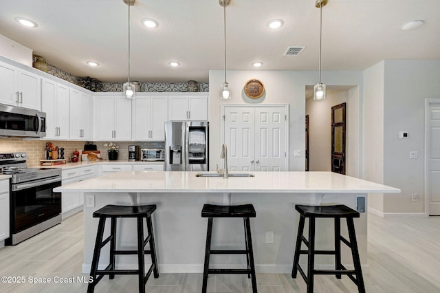 2365 Roygaris St NW, Palm Bay, FL 32907 - kitchen featuring stainless steel appliances, a sink, light countertops, backsplash, and white cabinetry