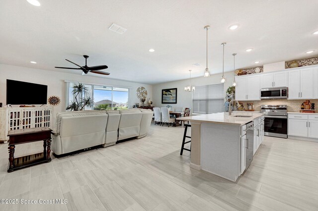 2365 Roygaris St NW, Palm Bay, FL 32907 - kitchen with stainless steel appliances, a sink, open floor plan, light countertops, and a breakfast bar area