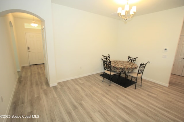 8342 Laguna Cir, Micco, FL 32976 - dining area with arched walkways, light wood-style floors, a chandelier, and baseboards