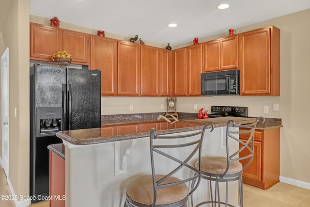 681 Ventura Dr, Satellite Beach, FL 32937 - kitchen with black appliances, a kitchen island, recessed lighting, a breakfast bar, and dark stone counters