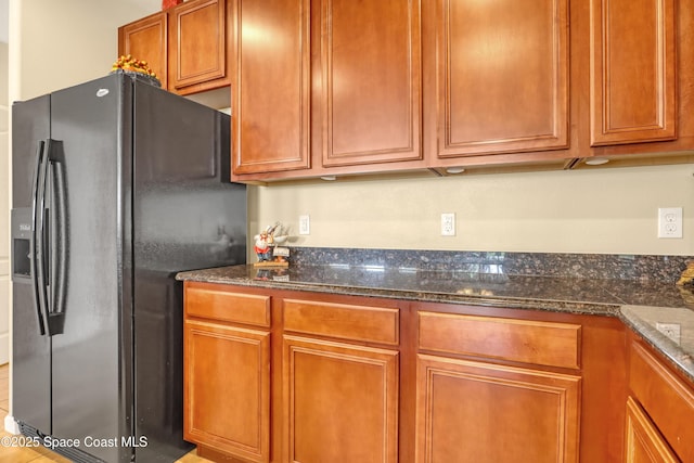 681 Ventura Dr, Satellite Beach, FL 32937 - kitchen featuring black fridge, dark stone countertops, and brown cabinets