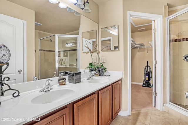 681 Ventura Dr, Satellite Beach, FL 32937 - bathroom with tile patterned floors, a shower stall, double vanity, a spacious closet, and baseboards