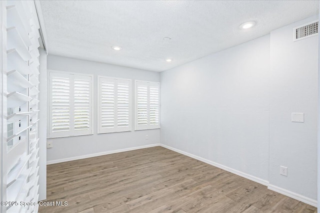 817 Seven Gables Cir SE, Palm Bay, FL 32909 - empty room featuring wood finished floors, a textured ceiling, baseboards, and recessed lighting