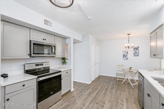 817 Seven Gables Cir SE, Palm Bay, FL 32909 - kitchen with stainless steel appliances, a textured ceiling, a chandelier, gray cabinets, and light countertops