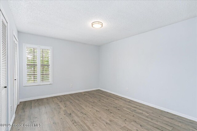 817 Seven Gables Cir SE, Palm Bay, FL 32909 - unfurnished bedroom featuring wood finished floors, a textured ceiling, baseboards, and a closet