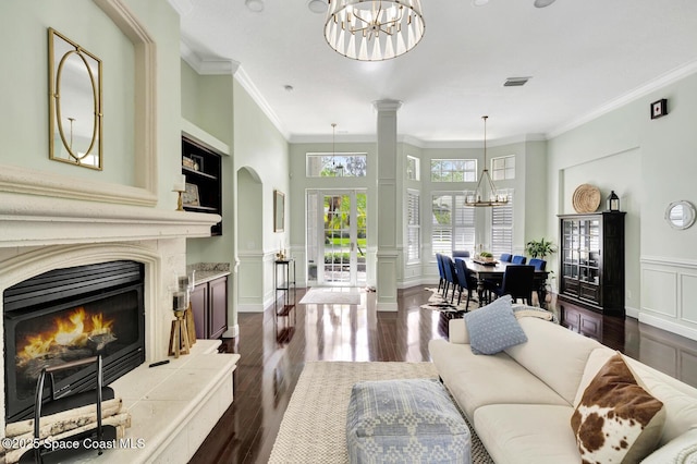105 38th Ct, Vero Beach, FL 32968 - living room featuring a chandelier, dark wood-style floors, ornamental molding, a decorative wall, and a premium fireplace