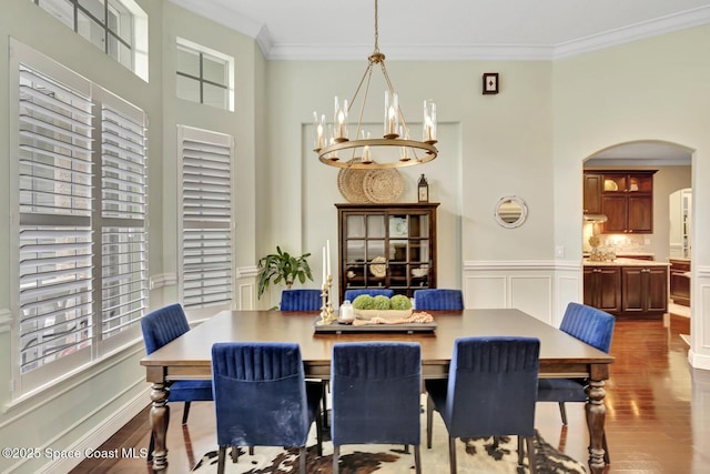 105 38th Ct, Vero Beach, FL 32968 - dining area with arched walkways, ornamental molding, dark wood-style flooring, a chandelier, and wainscoting