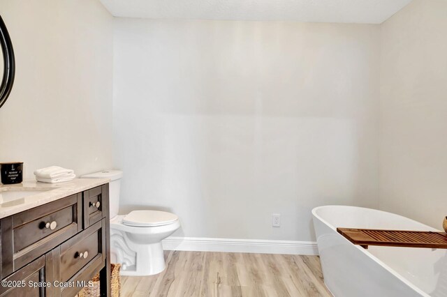 105 38th Ct, Vero Beach, FL 32968 - bathroom featuring a freestanding tub, wood finished floors, vanity, toilet, and baseboards