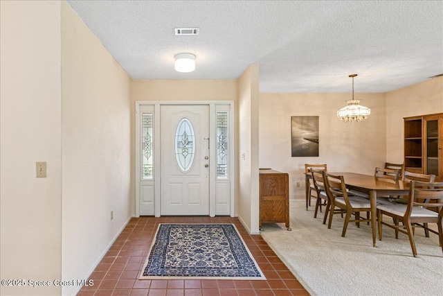 1181 Fairway Ct NE, Palm Bay, FL 32905 - foyer with a chandelier, a textured ceiling, dark tile patterned flooring, and baseboards