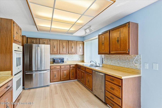 1181 Fairway Ct NE, Palm Bay, FL 32905 - kitchen featuring stainless steel appliances, a sink, light wood-style flooring, light countertops, and tasteful backsplash