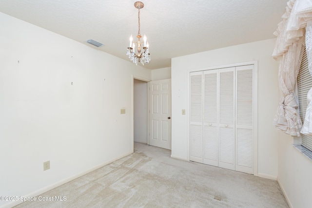 1080 Mayflower Ave, Melbourne, FL 32940 - unfurnished bedroom with a chandelier, carpet floors, a closet, baseboards, and a textured ceiling