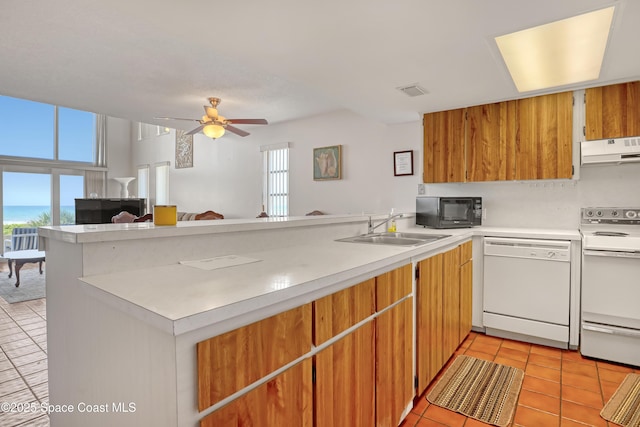 5050 Ocean Beach Blvd Unit 309, Cocoa Beach, FL 32931 - kitchen featuring white appliances, under cabinet range hood, a sink, a peninsula, and light countertops