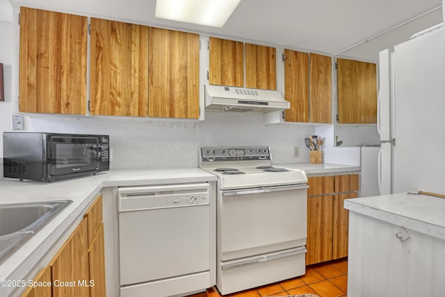 5050 Ocean Beach Blvd Unit 309, Cocoa Beach, FL 32931 - kitchen with under cabinet range hood, white appliances, light countertops, light tile patterned floors, and brown cabinetry