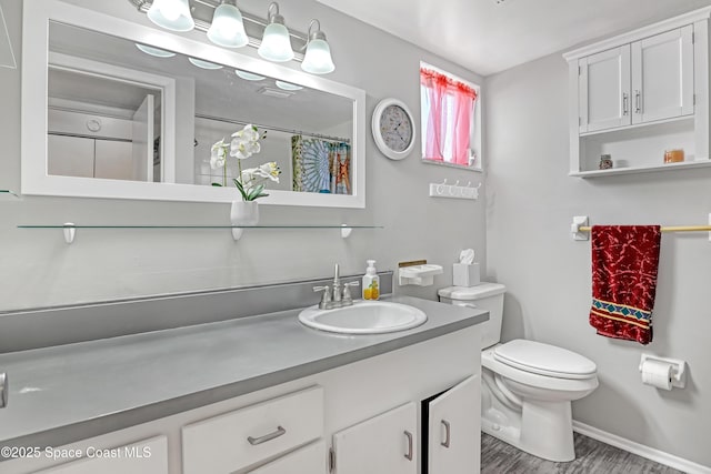 5050 Ocean Beach Blvd Unit 309, Cocoa Beach, FL 32931 - bathroom featuring vanity, toilet, wood finished floors, and baseboards